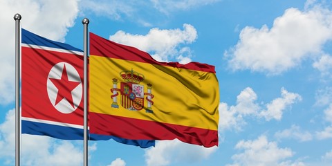 North Korea and Spain flag waving in the wind against white cloudy blue sky together. Diplomacy concept, international relations.