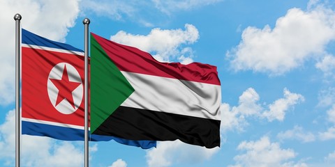 North Korea and Sudan flag waving in the wind against white cloudy blue sky together. Diplomacy...