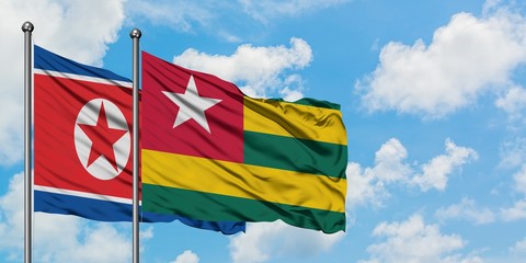 North Korea and Togo flag waving in the wind against white cloudy blue sky together. Diplomacy concept, international relations.