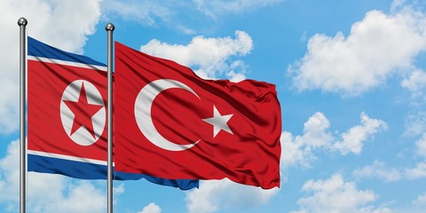 North Korea and Turkey flag waving in the wind against white cloudy blue sky together. Diplomacy concept, international relations.