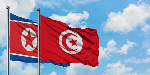 North Korea and Tunisia flag waving in the wind against white cloudy blue sky together. Diplomacy...