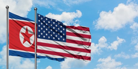 North Korea and United States flag waving in the wind against white cloudy blue sky together. Diplomacy concept, international relations.