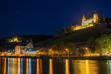 Fototapeta na wymiar Die Festung Marienburg und die Wallfahrtskirche Käppele in Würzburg bei Nacht mit Spiegelungen im Main