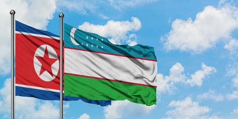 North Korea and Uzbekistan flag waving in the wind against white cloudy blue sky together. Diplomacy concept, international relations.