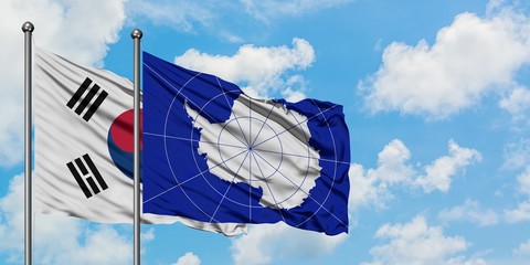 South Korea and Antarctica flag waving in the wind against white cloudy blue sky together....