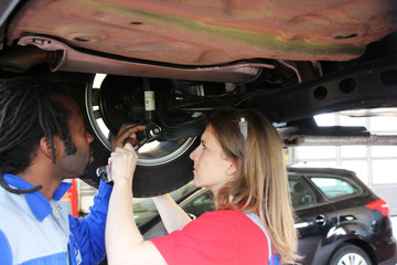 Man and woman working together repairing a car in the Automobile garage