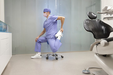 Dentist stretching legs.Caucasian man  exercising on dental mobile saddle in his office.