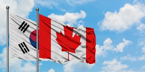 South Korea and Canada flag waving in the wind against white cloudy blue sky together. Diplomacy...