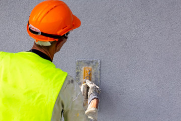 Worker applying decorative plaster on wall