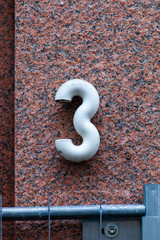 rounded number 3 on red granite wall