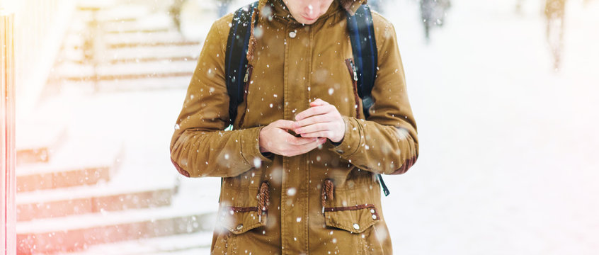 A man in a brown jacket is walking in a snowfall. Snowstorm in an urban environment. Abstract blurred winter weather background