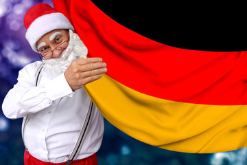 Santa Claus with a beard holds a beautiful colored national flag of the state of Germany on fabric, concept of tourism, New Year and Christmas, economic and political prospects