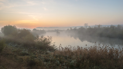 Sunrise over the hills with fog over a river