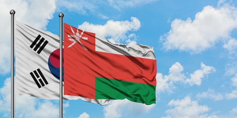 South Korea and Oman flag waving in the wind against white cloudy blue sky together. Diplomacy concept, international relations.