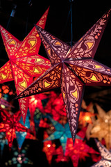 Festive lightning decorations, colorful star lanterns hanging on european Christmas market.
