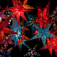 Festive lightning decorations, colorful star lanterns hanging on european Christmas market.