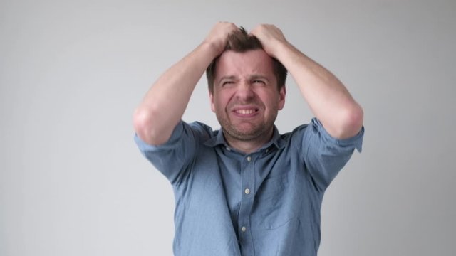 Desperate annoyed european man in rage and anger tearing his hair out.