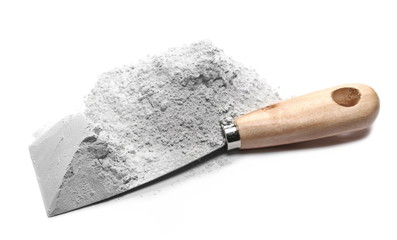 Pile of cement powder and metal industrial working spatula tool isolated on white