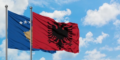 Kosovo and Albania flag waving in the wind against white cloudy blue sky together. Diplomacy concept, international relations.
