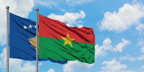 Kosovo and Burkina Faso flag waving in the wind against white cloudy blue sky together. Diplomacy concept, international relations.