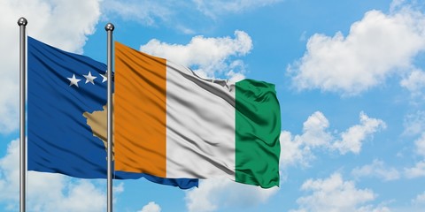 Kosovo and Cote D'Ivoire flag waving in the wind against white cloudy blue sky together. Diplomacy...