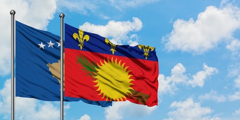 Kosovo and Guadeloupe flag waving in the wind against white cloudy blue sky together. Diplomacy concept, international relations.