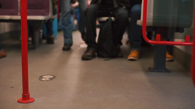 Feet of a passenger walking on a train car. The passenger chooses a seat.
