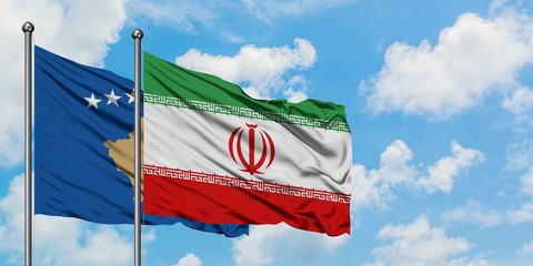 Kosovo and Iran flag waving in the wind against white cloudy blue sky together. Diplomacy concept, international relations.