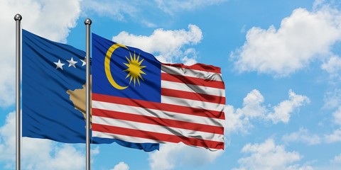 Kosovo and Malaysia flag waving in the wind against white cloudy blue sky together. Diplomacy concept, international relations.