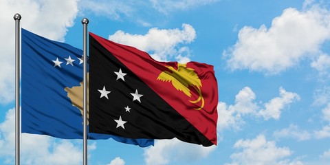 Kosovo and Papua New Guinea flag waving in the wind against white cloudy blue sky together. Diplomacy concept, international relations.