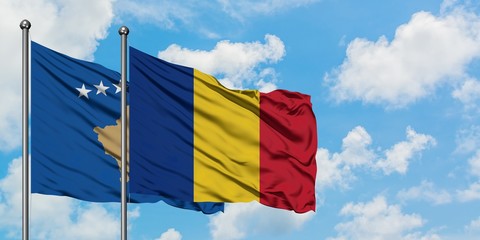 Kosovo and Romania flag waving in the wind against white cloudy blue sky together. Diplomacy concept, international relations.