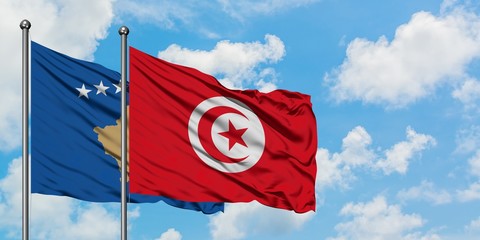 Kosovo and Tunisia flag waving in the wind against white cloudy blue sky together. Diplomacy concept, international relations.