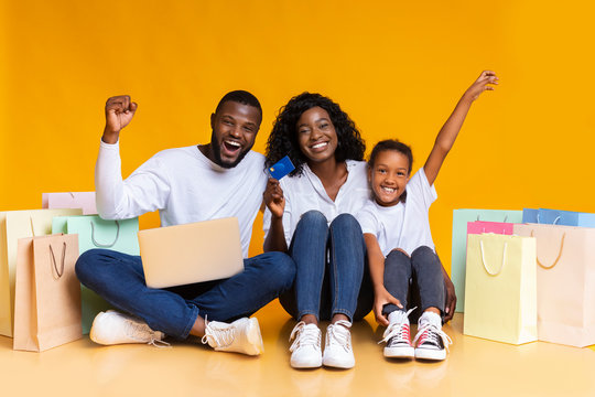 Happy black family with laptop, credit card and shopping bags.