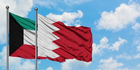 Kuwait and Bahrain flag waving in the wind against white cloudy blue sky together. Diplomacy concept, international relations.