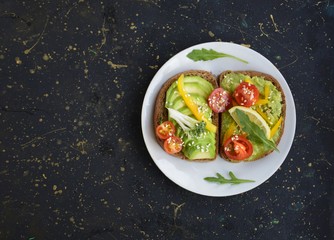 Fototapeta na wymiar sandwiches with avocado and cherry tomatoes in a white plate on a dark background