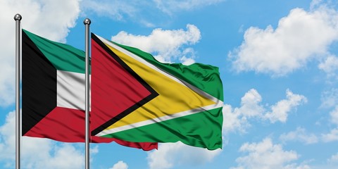 Kuwait and Guyana flag waving in the wind against white cloudy blue sky together. Diplomacy concept, international relations.