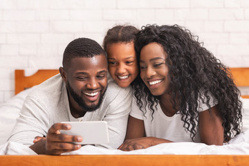 Obraz premium Happy afro man taking selfie with his wife and daughter