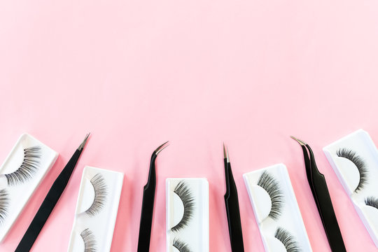 Many different tools for eye lash extension on trendy pastel pink background. False eyelashes and tweezers. Beauty shop. Makeup cosmetics. Top view, flat lay. Place for text. Layout. Copy space