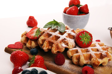 Traditional belgian waffles with fresh blueberries, sugar and raspberries on rustic table