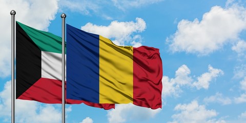 Kuwait and Romania flag waving in the wind against white cloudy blue sky together. Diplomacy...