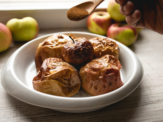 Naklejka na ściany i meble Baked apples, sprinkled with cinnamon and honey in a ceramic dish