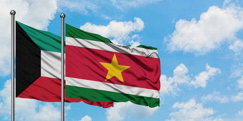 Kuwait and Suriname flag waving in the wind against white cloudy blue sky together. Diplomacy concept, international relations.