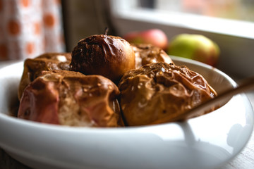 Baked apples, sprinkled with cinnamon and honey in a ceramic dish
