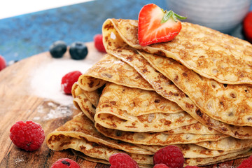 Delicious Tasty Homemade crepes or pancakes with raspberries and mint on rustic background