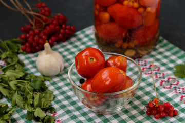 Homemade salted tomatoes in glass bowl and jar on a dark background, Fermented food