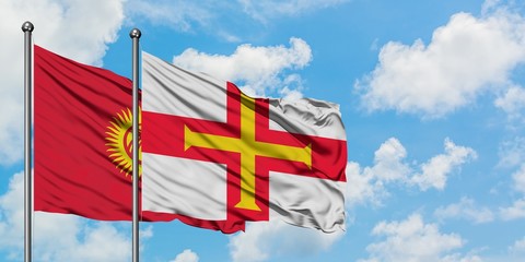 Kyrgyzstan and Guernsey flag waving in the wind against white cloudy blue sky together. Diplomacy concept, international relations.