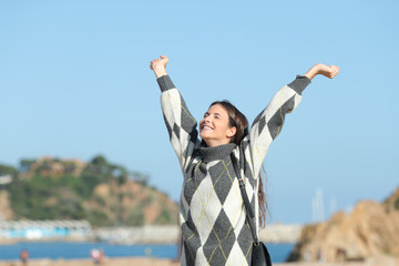 Excited girl in winter raising arms on the beach