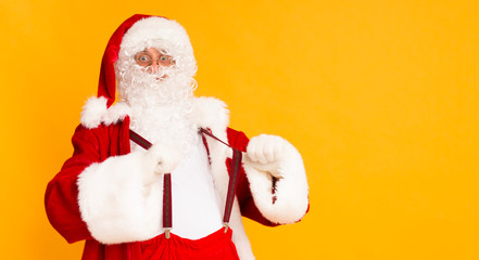 Funny Santa showing his Christmas suspenders over orange