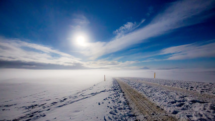 Route en islande à travers la neige qui s'enfonce dans les nuages à la lueur de la lune 