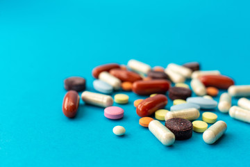 A scattered handful of colored pills on a blue background. Medical concept